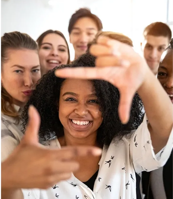 Diverse group of smiling professionals, one framing the shot with her hands